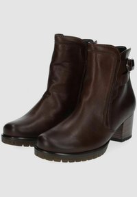 Botas de cuero marrón hasta el tobillo con un ligero tacón, que presentan un detalle de correa lateral, puntera redondeada y una suela texturizada para mayor agarre.
