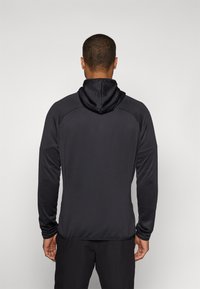 Schwarzer Herren-Hoodie mit glatter Textur, der ein figurbetontes Design, lange Ärmel und eine Kapuze mit Kordelzug aufweist. Keine sichtbaren Logos oder Muster.