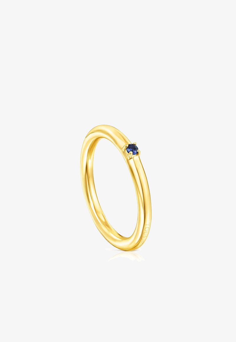Goldring mit einem glatten, abgerundeten Design, versehen mit einem kleinen blauen Edelstein, der in einer Fassung sitzt. Reflektierende und polierte Oberflächenbeschaffenheit.