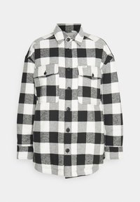 Black and white checkered flannel shirt with two front pockets, button closure, and a classic collar design. Soft, textured fabric.