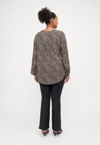 Μπλούζα με λεοπάρ σχέδιο, μακρύ μανίκι, και στρογγυλή εσοχή στο πίσω μέρος. Συνδυάζεται με μαύρες παντελόνες και ψηλοτάκουνα σανδάλια.