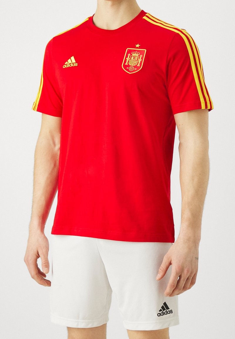 Rode T-shirt met korte mouwen en gele accenten, voorzien van het embleem van het Spaanse nationale team. Gemaakt van een gladde stof. Gekoppeld aan witte shorts.