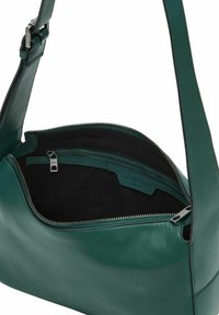 Zielona torba na ramię ze skóry z regulowanym paskiem i otwartym zamkiem na górze, ukazującym czarne wnętrze oraz wewnętrzną kieszeń na suwak.