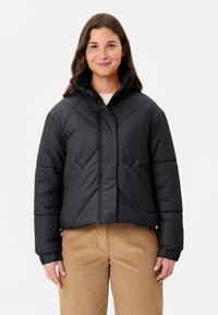 Veste matelassée courte noire avec un col haut, des coutures horizontales et diagonales, et des poches latérales. Texture douce avec des poignets élastiqués.