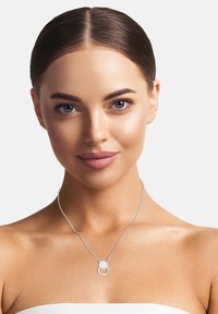 Sølv kædedesign med en cirkulær vedhæng med en struktureret overflade, der fremhæver en central funklende detalje.