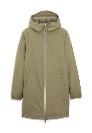 Homme portant une veste d'hiver kaki à capuche, longueur genou, avec fermeture éclair frontale et poches latérales zippées, debout devant un fond uni.