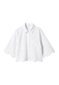 Blouse blanche à manches courtes en tissu de dentelle, avec un ourlet, un col et une patte de boutonnage festonnés. Le motif comprend des dessins floraux complexes.