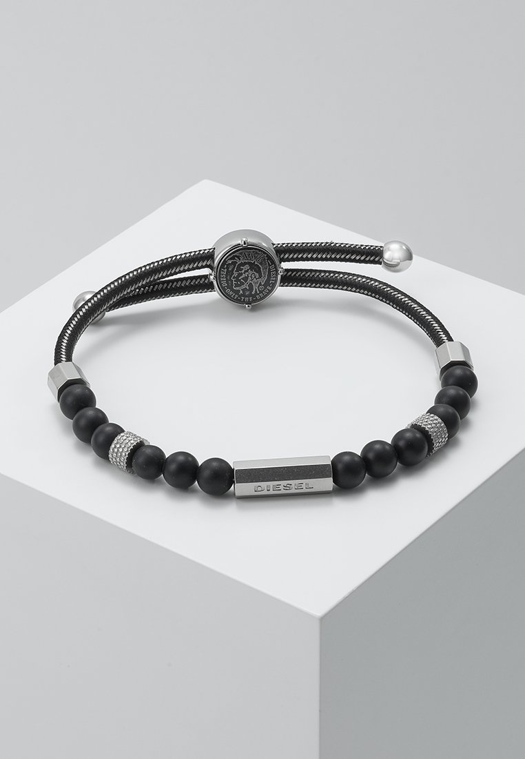 Bracciale nero caratterizzato da un design con perline, con pietre nere opache e accenti in argento, una chiusura a logo rotondo e una placca rettangolare "DIESEL".