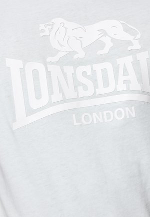 Svijetlosiva majica s grafikom bijelog lava i natpisom "Lonsdale London". Napravljena od mekanog, prozračnog pamuka s glatkom teksturom.