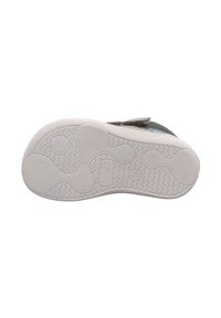 Zapato de tela gris con suela de goma blanca, que presenta patrones texturizados y una correa de velcro para un cierre seguro. Base diseñada para tracción.