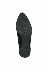 Suela de zapato negra con goma texturizada para agarre, presentando una parte delantera lisa y redondeada con un sutil patrón de ondas. Talla 37 indicada en la suela.
