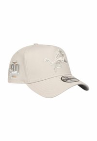 Beige Kappe mit strukturierter Oberfläche, versehen mit einem gestickten Löwenlogo und einem 90-Jahr-Jubiläums-Patch an der Seite. Design mit gebogenem Schirm.