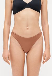 Bruine bikini onderbroek met een gladde textuur, minimale bedekking en een lage taille. Het heeft dunne zijbanden en geen zichtbare hardware.