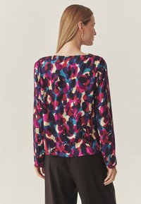 Pikkade varrukatega blouse, millel on mitmevärviline abstraktne muster purpur- ja roosa- ning sinise tooni kerge kangas.