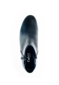 Chaussure en cuir noir avec un bout arrondi et une fermeture éclair sur le côté. Texture lisse et design simple sans motifs ni accents.
