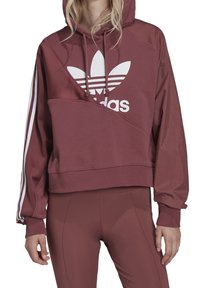 Sudadera corta color burdeos con el logo blanco de Adidas, que presenta una capucha, cordones y franjas laterales blancas. Tejido suave y texturizado con un diseño angular.
