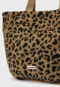 Geantă din fleece cu imprimeu leopard maro și negru, cu mânere bej și un mic tag rectangular cu logo-ul LIEWOOD pe față.