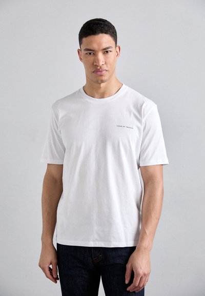 Witte t-shirt met korte mouwen, gemaakt van katoen, met een ronde halslijn en kleine tekst "TIGER OF SWEDEN" op de linkerbovenkant van de borst.