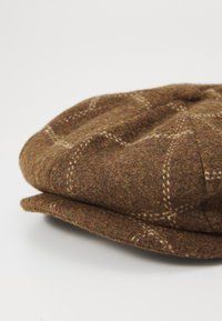 Brown wool cap with a textured finish, featuring a checked pattern in off-white lines, rounded shape, and a small top button detail.