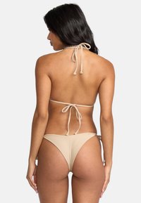 Beżowy bikini z teksturowanej tkaniny; trójkątny stanik z wiązaniami na szyję i niskim stanem majtek z minimalnym zakryciem oraz bocznymi wiązaniami.