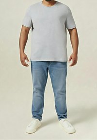 Jasnoszara koszulka z krótkim rękawem w połączeniu z jasnoniebieskimi dżinsami i białymi tenisówkami. Casualowy krój z okrągłym dekoltem i gładką fakturą.