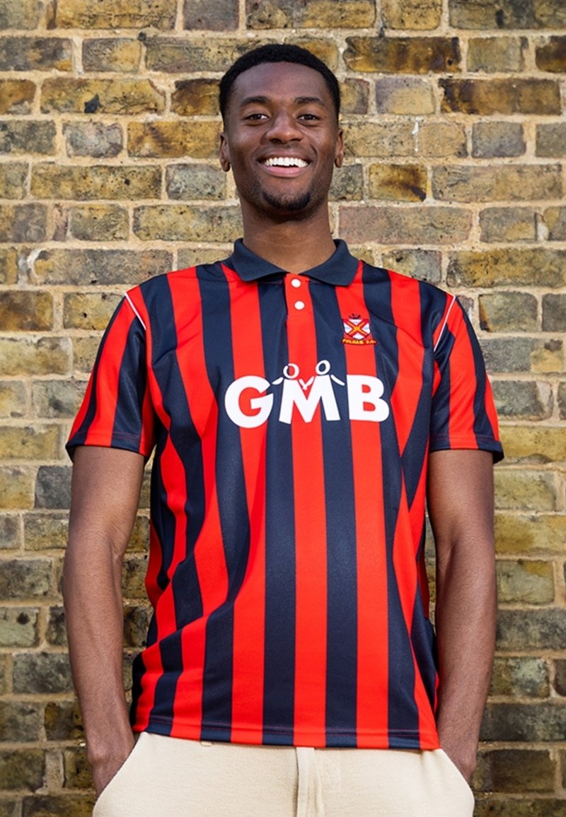 Rode en marineblauwe gestreepte polo met een kraag, voorzien van een wit logo "GMB" op de voorkant. Glad, synthetisch materiaal tegen een bakstenen muur.