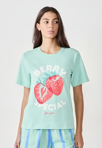 T-shirt in cotone verde menta con una grafica frontale di due fragole rosse e il testo "BERRY SPECIAL per te" in bianco. Maniche corte.