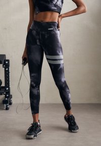 Černé a šedé legíny na cvičení se vzorem tie-dye, vysokým pasem, reflexními pruhy a hladkou, elastickou texturou látky.