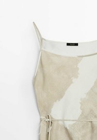 Robe beige sablon avec un motif crème marbré, bretelles spaghetti ajustables et taille à nouer. Texture lisse avec une coupe décontractée.