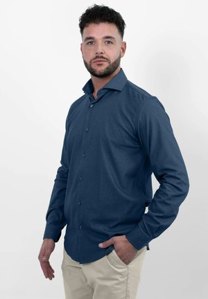 Donkerblauwe lange mouwen shirt met een button-down kraag, vervaardigd van een gestructureerde stof en een slim fit, gecombineerd met lichte broek.