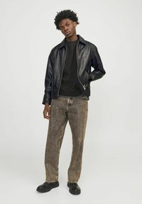 Black leather jacket, black sweatshirt, and light brown patterned jeans. Black shoes with a thick sole. Casual fit, minimalistic design.