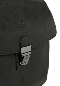 Czarna skórzana torba o gładkim wykończeniu, z klapką zamykającą i błyszczącym metalowym detalem z klamrą. Subtelne wytłoczone logo marki jest widoczne.