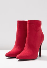 Stivaletti in suede rosso con punta affilata, tacco sottile a stiletto e design senza cuciture, dotati di una vestibilità alta alla caviglia e una texture morbida.