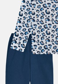 Leopard print top in shades of blue on a white background, paired with solid navy soft pants. Cotton blend, casual design.