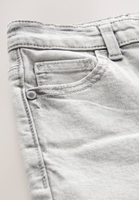 Jean denim gris avec une petite poche avant, des détails cousus et un bouton métallique près de la ceinture. Texture lisse.