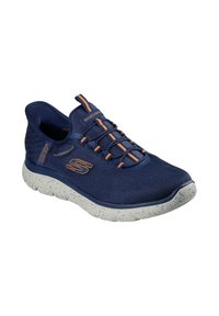 Zapato Skechers azul marino con parte superior de malla impermeable, cordones de correr y suela de espuma blanca moteada. Cuenta con talón texturizado para mayor agarre.