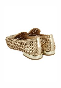 Bailarinas tejidas en oro con un exterior texturizado y un acento metálico en el talón. Suela plana con un diseño abierto y recortes decorativos.