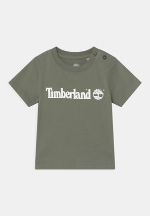 T-shirt vert olive pour tout-petit manches courtes, boutons pression à l'épaule et logo blanc « Timberland » avec emblème d'arbre sur le devant.