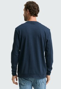 Marineblauwe gebreide pullover trui met lange mouwen, ronde hals en ribgebreide manchetten en zoom; zachte textuur, casual pasvorm. Alleen achteraanzicht.