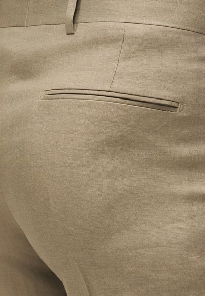 Μπεζ λινό παντελόνι σε κοντινή λήψη που δείχνει την πίσω τσέπη και τη λεπτομέρεια της θηλιάς της ζώνης.