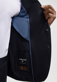 Navy-Blazer mit blauer Innenauskleidung; verfügt über eine Innentasche, Strellson-Label und ein elegantes Design. Glatte Textur, taillierter Schnitt, klassische Silhouette.