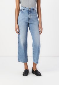 Jeans de cintura alta de tom azul claro com corte reto, apresentando um fecho frontal com botões, passes de cinto e detalhes discretos de desgaste.