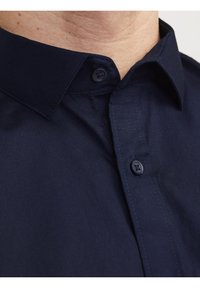 Camisa de algodón azul marino con cuello clásico, cierre frontal de botones y textura suave con detalles sutiles de costura.