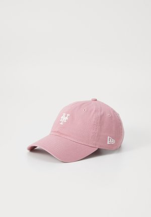 Casquette de baseball rose avec logo brodé blanc des New York Mets à l’avant et petit logo blanc sur le côté, exposée sur une surface blanche.