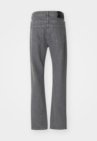 Sive ravne traperice prikazane straga s dva stražnja džepa i crnim kožnim logom branda na pojasu.