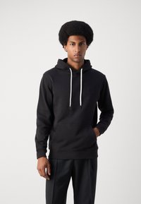 Hoodie noir en tissu doux, doté d'une poche kangourou, de cordons de serrage ajustables et d'un logo brodé sur la poitrine.