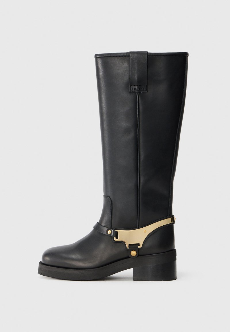 Mustad, mustadest nahast kõrged saapad, millel on kuldne metallist aksessuaariga rihm, tugev tald ja tasane põhi, samuti tugevdus tagumise aasaga.