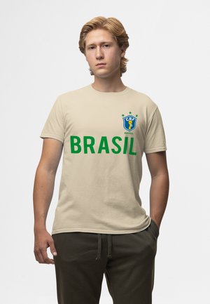 Beige bavlněné tričko s výrazným zeleným textem "BRASIL", modrou a žlutou nášivkou se hvězdami na levé části hrudi. Krátké rukávy, kulatý výstřih.