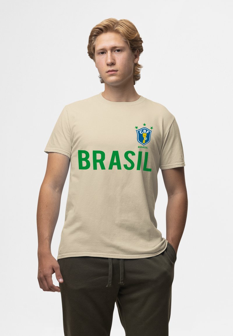 Beige bavlněné tričko s výrazným zeleným textem "BRASIL", modrou a žlutou nášivkou se hvězdami na levé části hrudi. Krátké rukávy, kulatý výstřih.