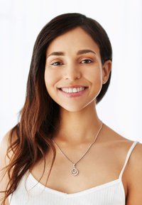 Sølv halskæde med sammenflettede cirkulære vedhæng, båret af en person med langt, lige hår, mod en lys baggrund.